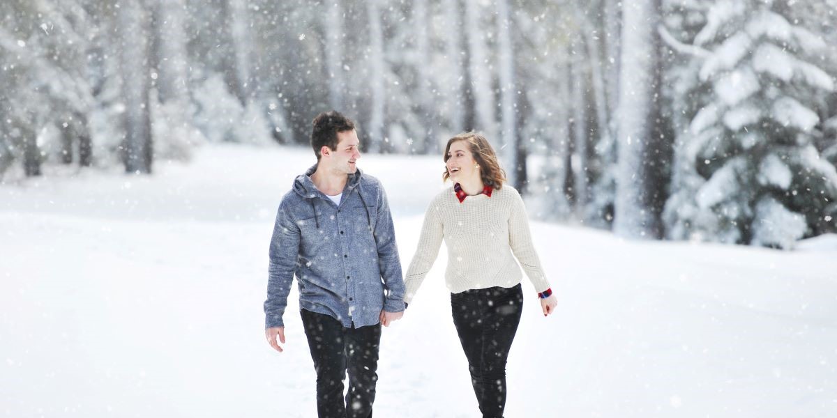 male female couple holding hands walking throw snowflakes